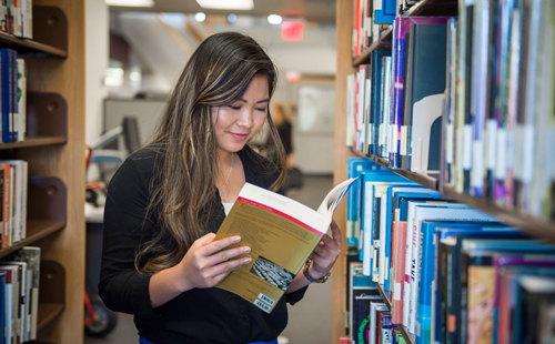 student in library reading book